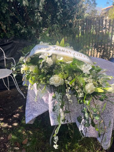 Composition florale élégante avec des fleurs blanches et feuillage vert sur une table.